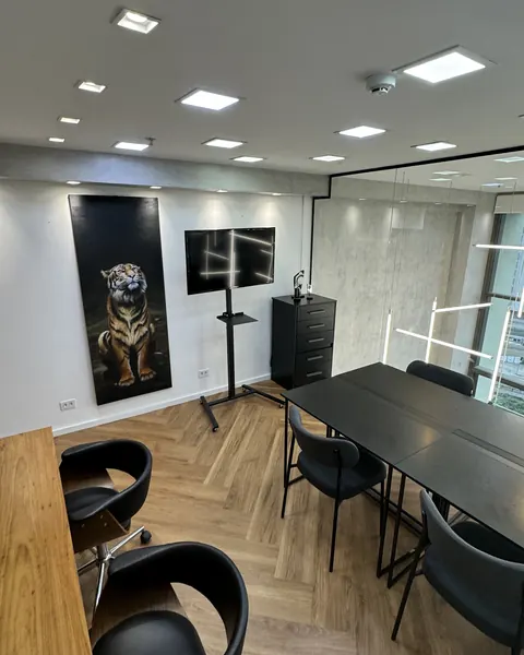 Studio meeting room with a black table, chairs and a realistic portrait painting on the wall.