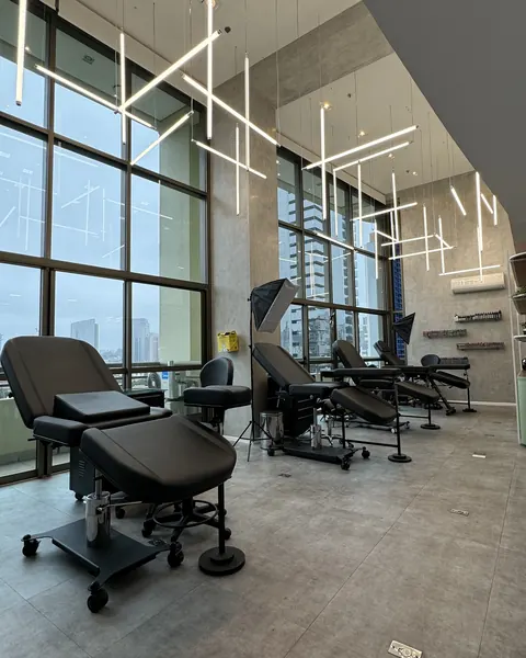 Studio floor with black tattoo beds, high ceilings and glass windows facing the city.