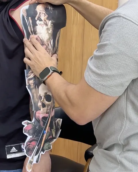 Printed full-sleeve composition placed on the client's arm, with Fernando Souza adjusting the fit.