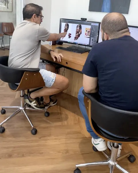 Fernando Souza at his desk, next to the client, building the design on the computer.